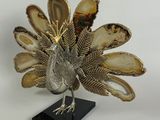 une image représentant une statue de paon en argent et en or posée sur un socle noir