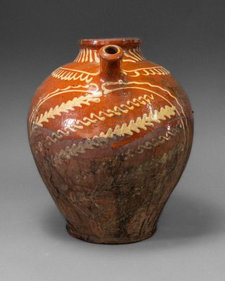 a brown vase with designs on it on a gray surface