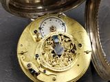 a gold pocket watch sitting on a table with a clock inside of it