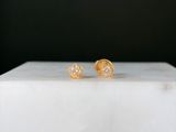 boucles d'oreilles en or et diamants posées sur une surface en marbre blanc