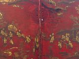 a red and gold screen with a painting of people on it