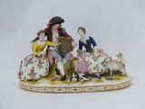 a figurine of three people sitting on a bench with a dog