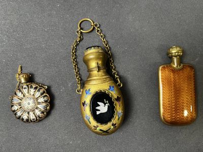 trois types différents de flacons de parfum et un collier posés sur une table