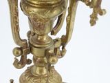 a gold vase on a stand on a white surface