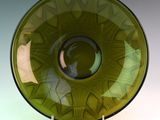 un bol en verre vert à bord noir, posé sur un socle