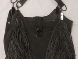 black leather purse with tassels hanging from it on a bed