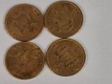 four quarters of gold coins sitting on top of a white surface