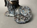 a statue of a dog that is laying down on the ground