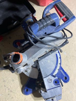 a blue circular saw sitting on the floor next to a black bag