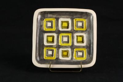 une assiette blanche ornée de carrés jaunes, posée sur un fond noir