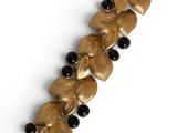 an image of a close up of a gold bracelet with black beads