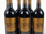 four bottles of wine are lined up on a white surface