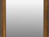 un miroir à cadre doré accroché à un mur gris