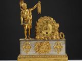 une statue en or représentant un homme tenant un oiseau et une horloge