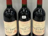 three bottles of red wine are lined up on a white surface