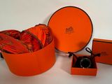 une boîte orange contenant une bague, posée à côté d'une paire de chaussures orange