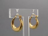 boucles d'oreilles créoles plaquées or présentées sur un présentoir en acrylique transparent