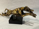 statue d'un chien courant sur un socle noir sur fond blanc