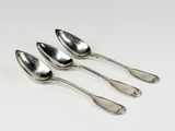 quatre cuillères en argent empilées les unes sur les autres sur une surface blanche
