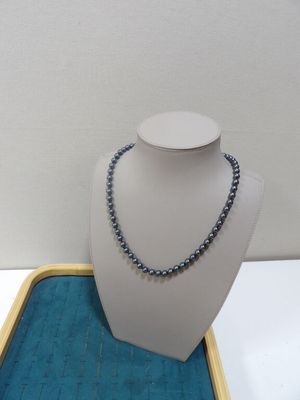 collier de perles grises présenté sur un plateau bleu avec un fond blanc