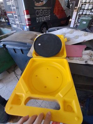Quelqu'un tient un objet jaune dans la main, devant un tas de vieilleries.