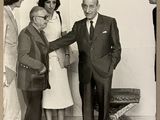 photographie en noir et blanc d'un groupe de personnes debout autour d'un homme en costume-cravate