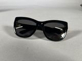 black cat eye sunglasses on a white surface with a pair of glasses
