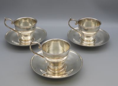 three silverplated cups and saucers on a saucer