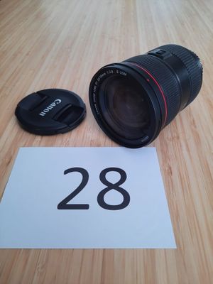 un objectif Canon 28 mm f/1,8 posé sur une table à côté d'un numéro 28