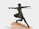 bronze statue of a woman holding a bow and arrow on a marble base