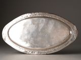 a silver oval tray with a decorative design on it
