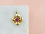 un gros plan d'un pendentif en forme de fleur en or, orné d'une pierre rose en son centre