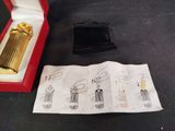 a gold lighter in a red box next to a piece of paper