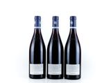 three bottles of red wine sitting on top of a white surface