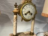 une horloge posée sur une table, avec une lampe à côté