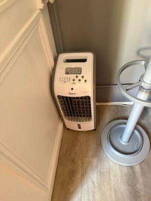 a small air conditioner sitting on the floor next to a chair