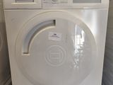 une photo d'une machine à laver blanche dans une petite pièce