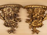 deux appliques murales en or richement décorées posées sur une table en bois