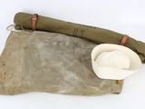 un chapeau et un sac enroulé posés par terre