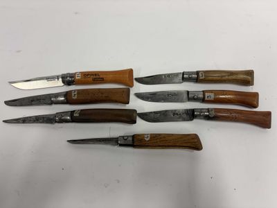 cinq types de couteaux différents sont alignés sur une surface blanche