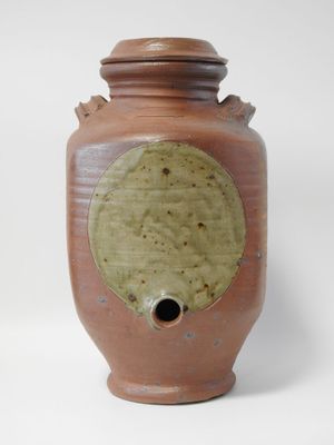 un vase marron troué posé sur une surface blanche