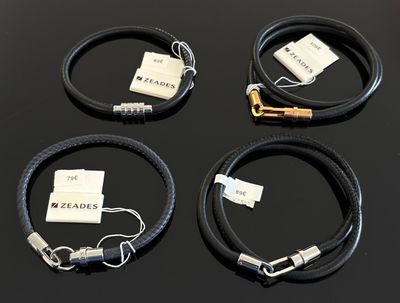 trois bracelets en cuir noir ornés d'étiquettes blanches, posés sur une table
