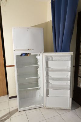 un réfrigérateur blanc et un rideau bleu dans une pièce