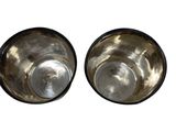 two metal bowls sitting next to each other on a white surface