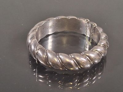 a silver bracelet with a chain on a black surface