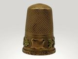 a gold thimble with a design on it