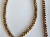 un gros plan d'un collier et d'un bracelet posés sur une surface blanche
