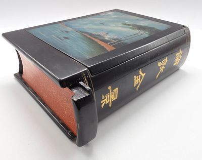 un livre noir portant des inscriptions en chinois, posé sur une surface blanche