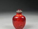 a red vase with a silver lid sitting on a white surface
