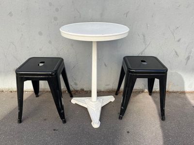 two stools and a table in front of a wall